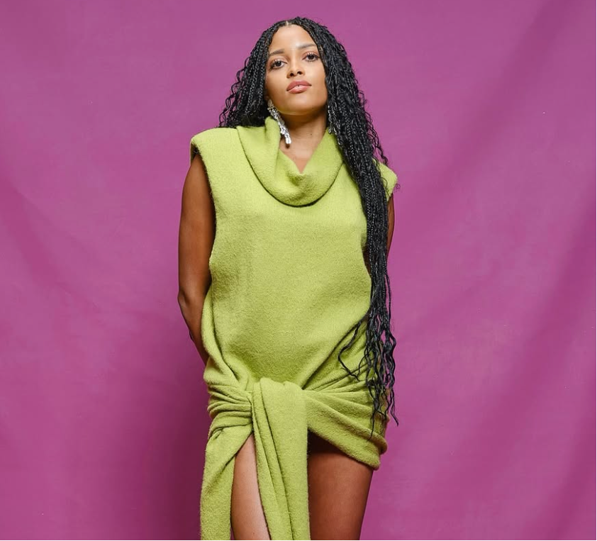 Woman wearing a green dress with a high slit on a purple background