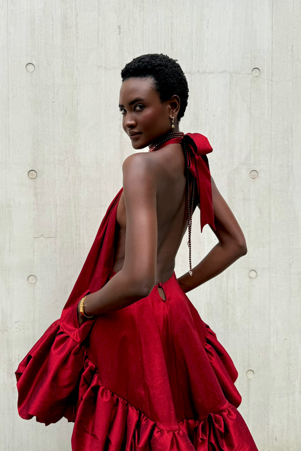 Woman wearing a red dress with a textured light gray background