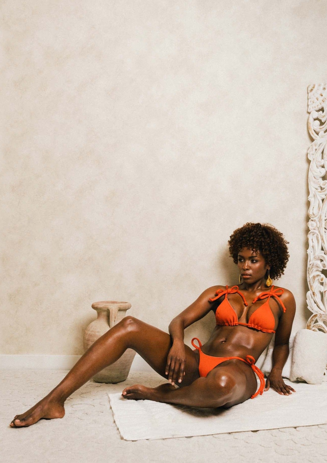 woman sitting on the ground in a matching orange bikini set